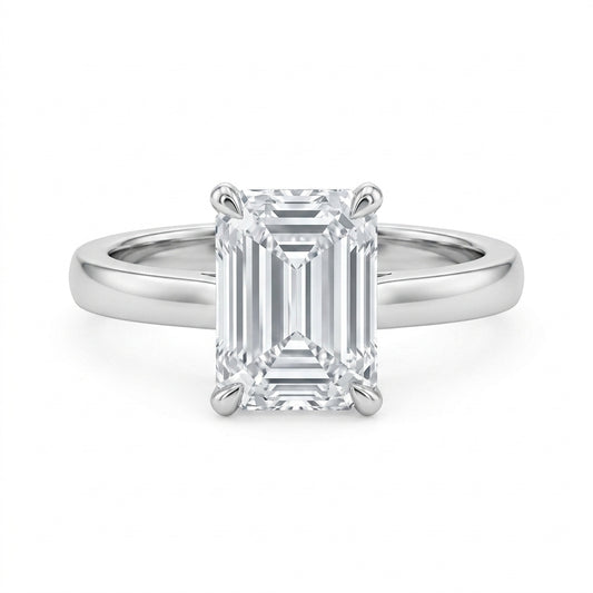 Emerald cut moissanite solitaire engagement ring with high-polish silver plain band on white background.