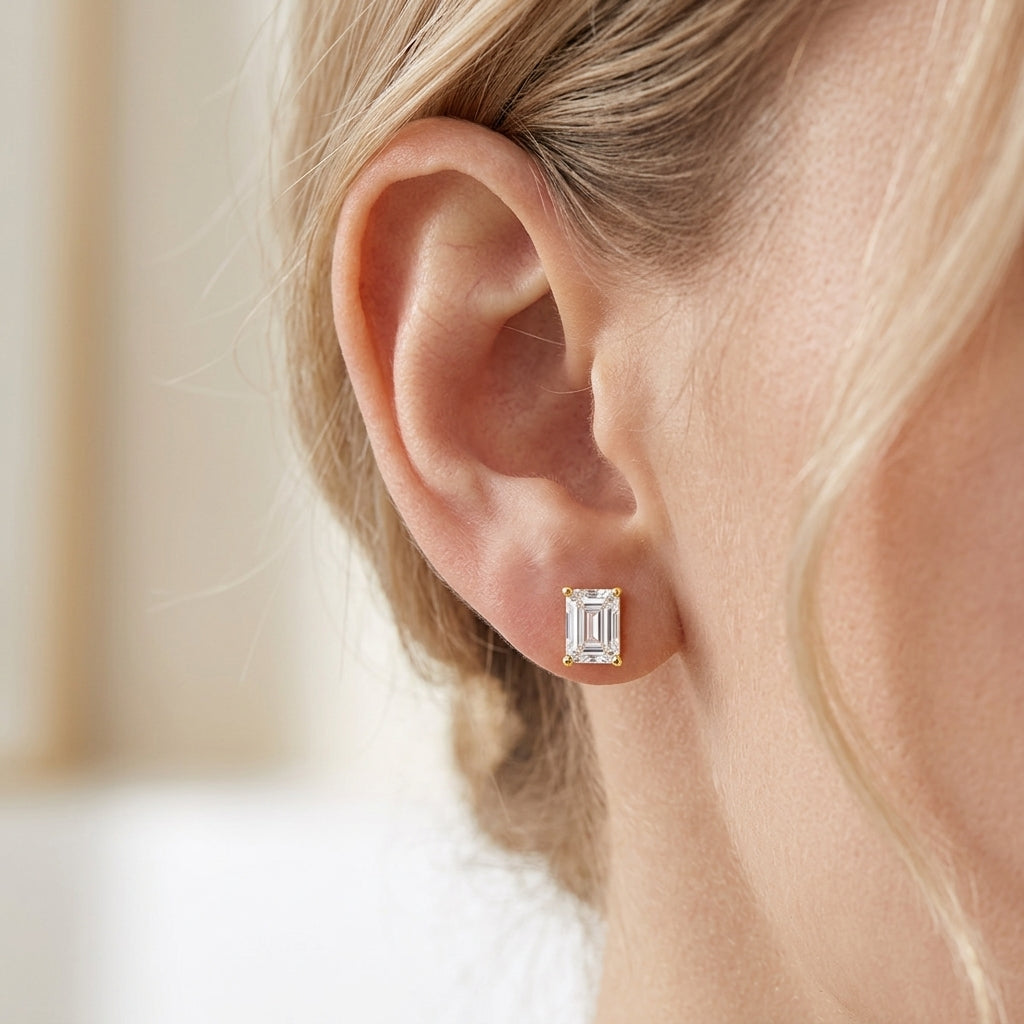 Close-up view of model showing emerald cut moissanite stud earring on ear.