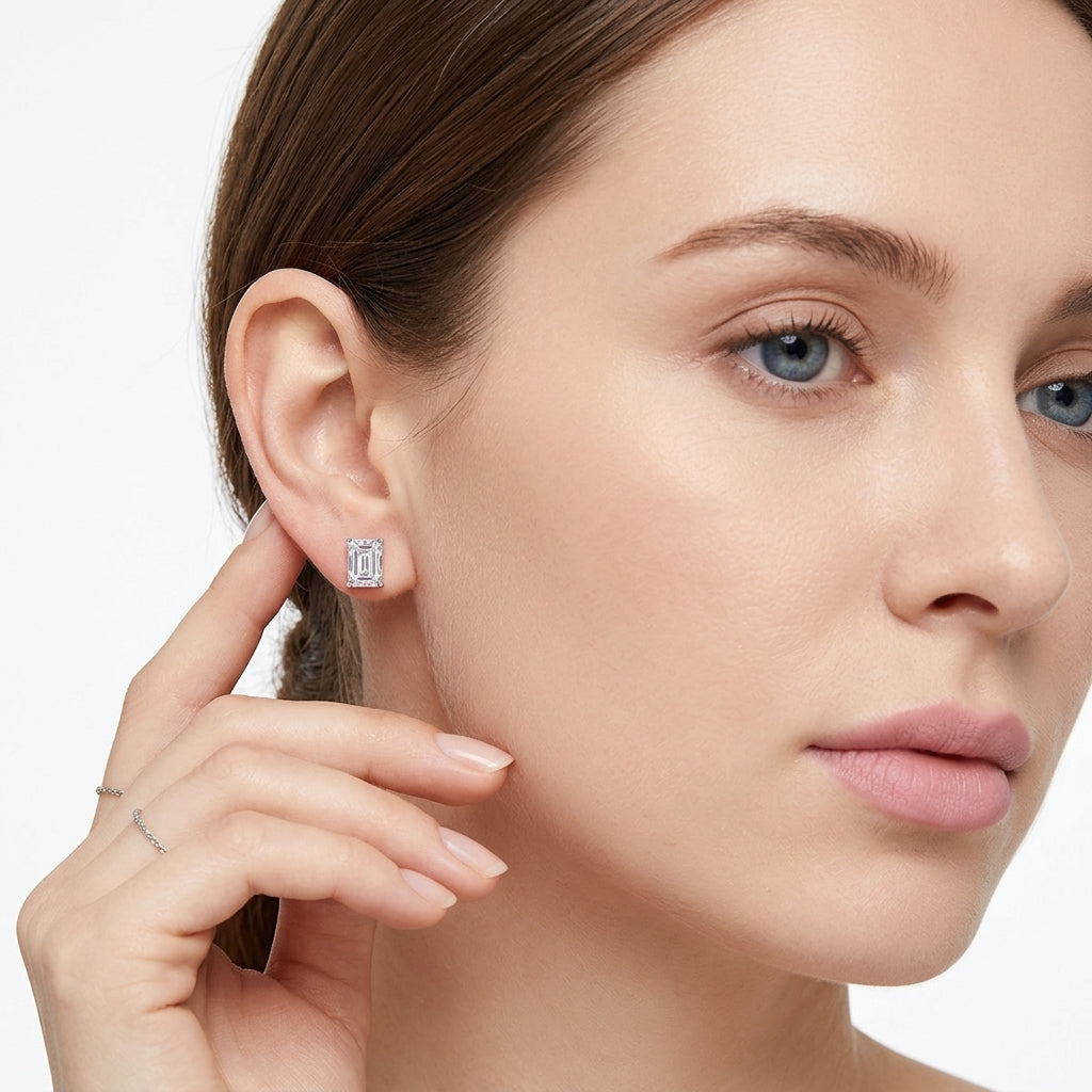 Model wearing 5x7mm emerald cut moissanite solitaire stud earrings.