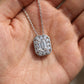 Close-up shot of emerald cut diamond octagonal halo bezel pendant resting on palm.