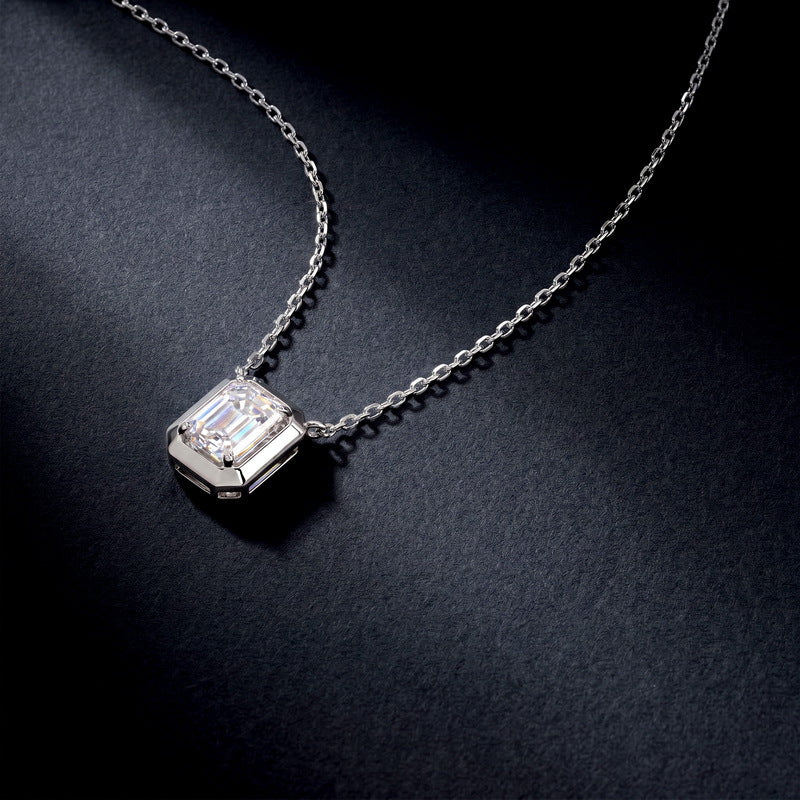 Emerald cut diamond solitaire pendant necklace displayed on dark background.