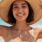Model wearing emerald cut diamond solitaire pendant necklace with straw hat.