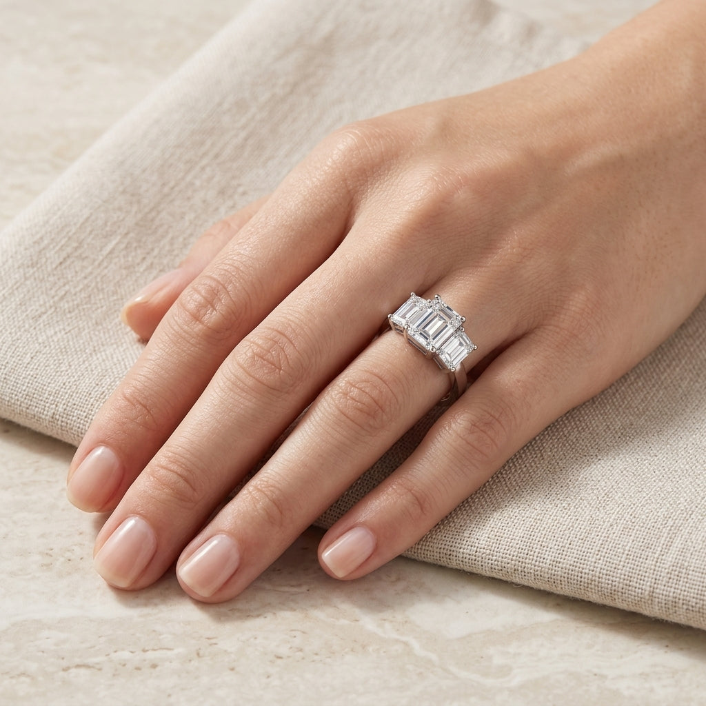 Full hand shot of model wearing emerald cut three stone engagement ring.
