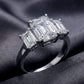 Perspective shot of emerald cut lab grown diamond three stone ring on dark silk.