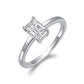 Silver emerald cut moissanite solitaire ring with plain shank standing on display.