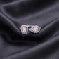 Front view of emerald and pear cut lab grown diamond toi et moi halo ring on dark black silk fabric