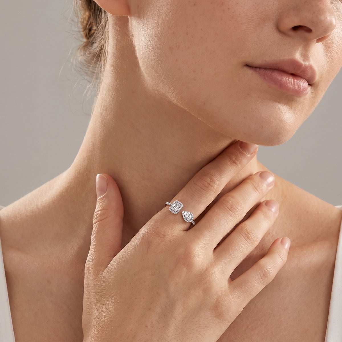 Woman wearing emerald and pear cut lab grown diamond toi et moi open ring on finger