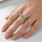 High-angle hand view of a model wearing an emerald snake bypass adjustable open ring on her index finger.