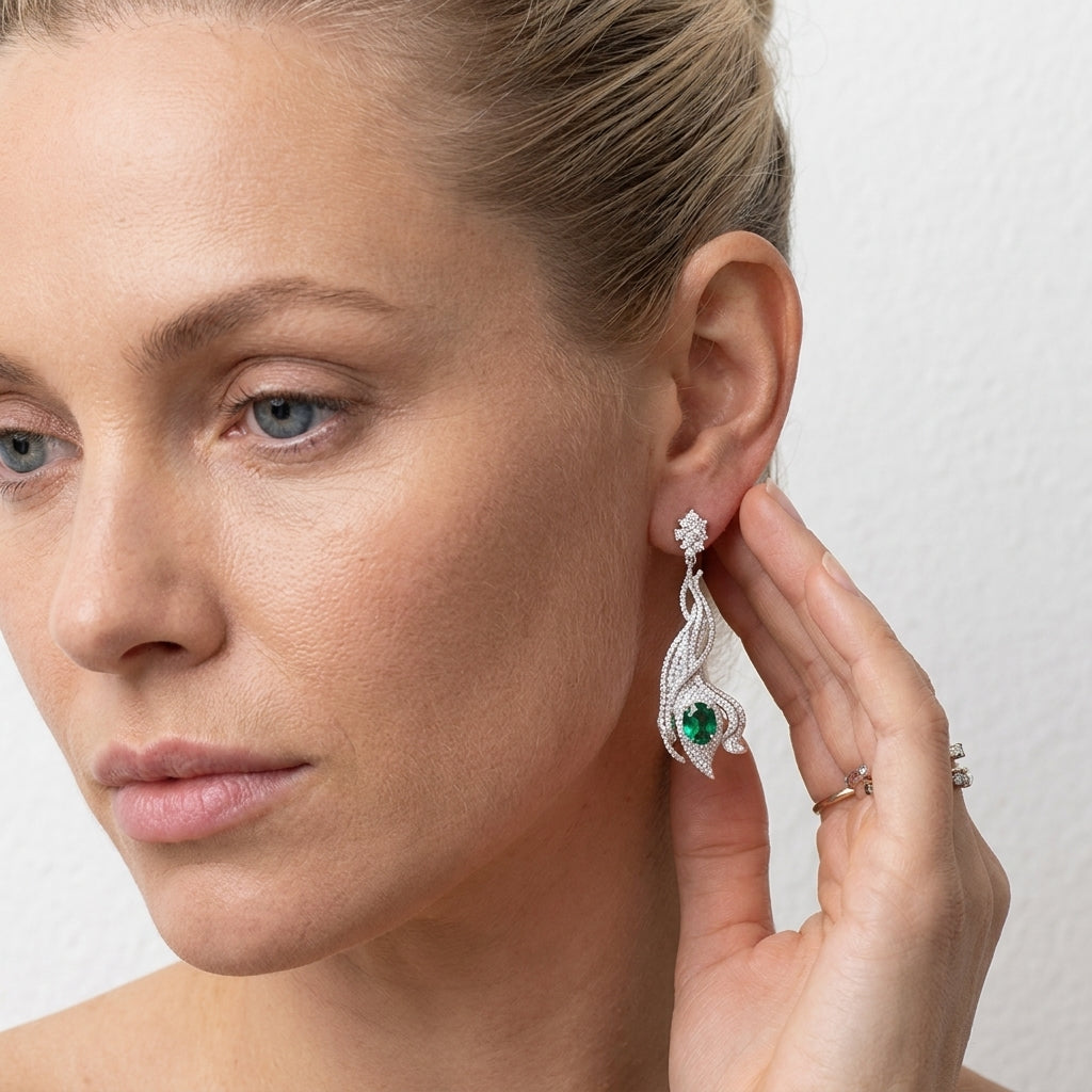 Model wearing 3.14ct oval-cut emerald wave earrings, front view, high fashion aesthetic.