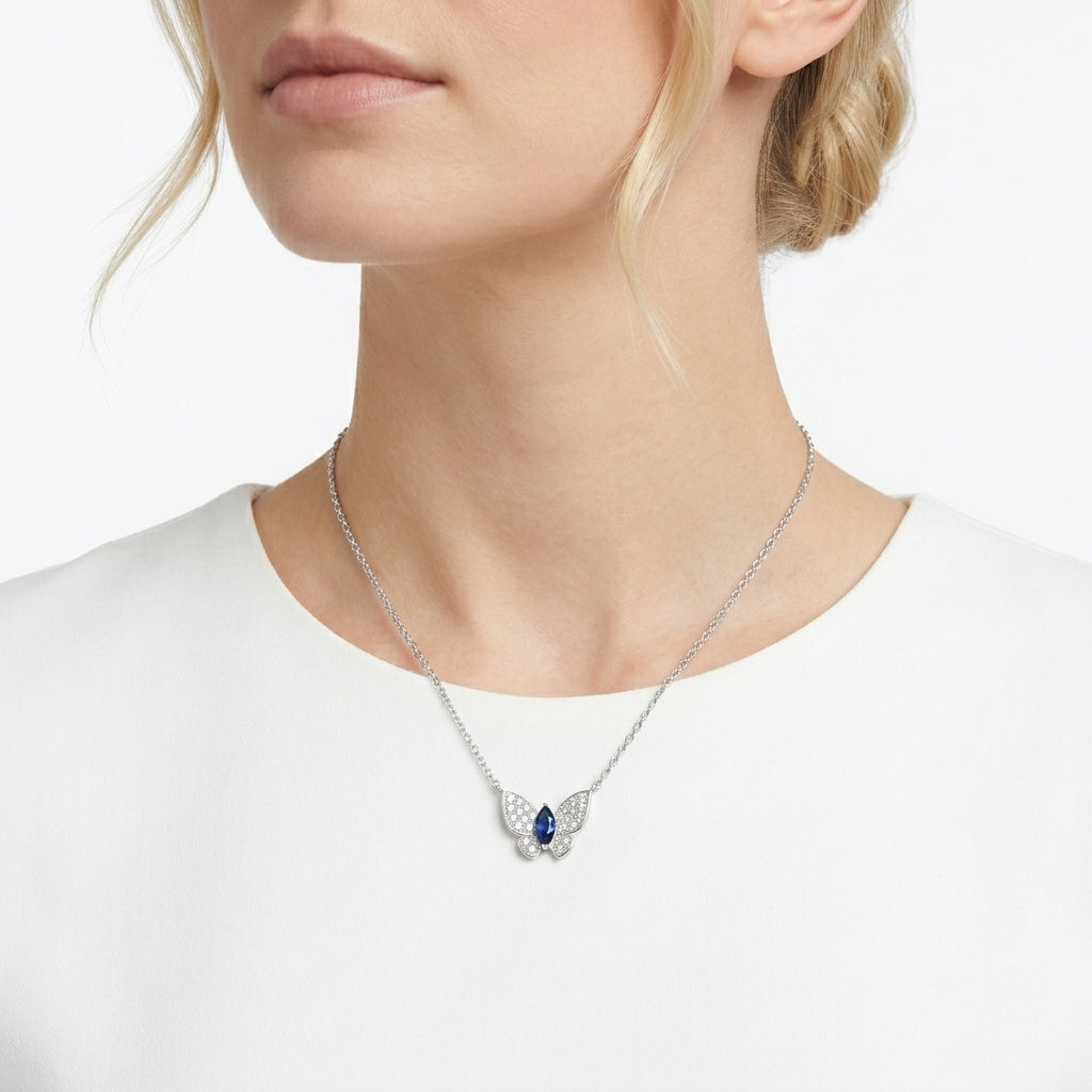 Close-up lifestyle portrait view of a model showcasing an ethereal sapphire butterfly statement pendant necklace.