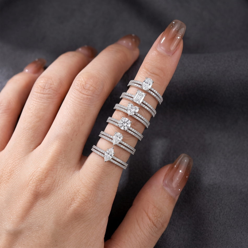 Hand displaying various solitaire and pave stacking ring sets in fancy cuts.