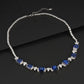 Overhead dark flat lay view of a fine jewelry blue sapphire gemstone collar necklace showcasing flexible linked prongs.