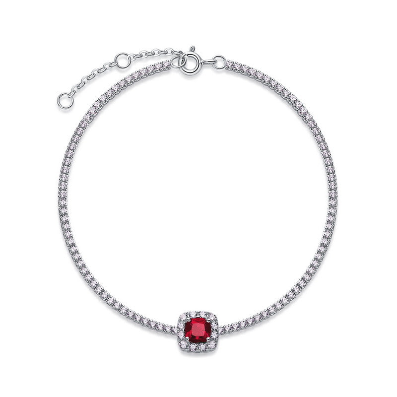 Overhead circular display view of a fine jewelry cushion-cut ruby halo tennis bracelet on a white backdrop.