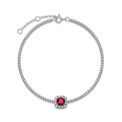 Overhead circular display view of a fine jewelry cushion-cut ruby halo tennis bracelet on a white backdrop.
