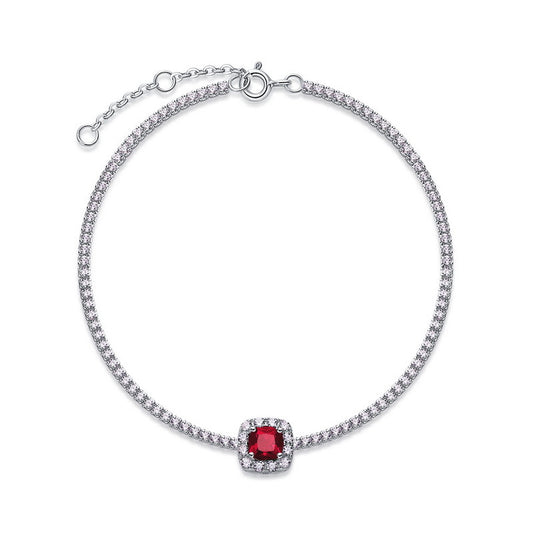Overhead circular display view of a fine jewelry cushion-cut ruby halo tennis bracelet on a white backdrop.