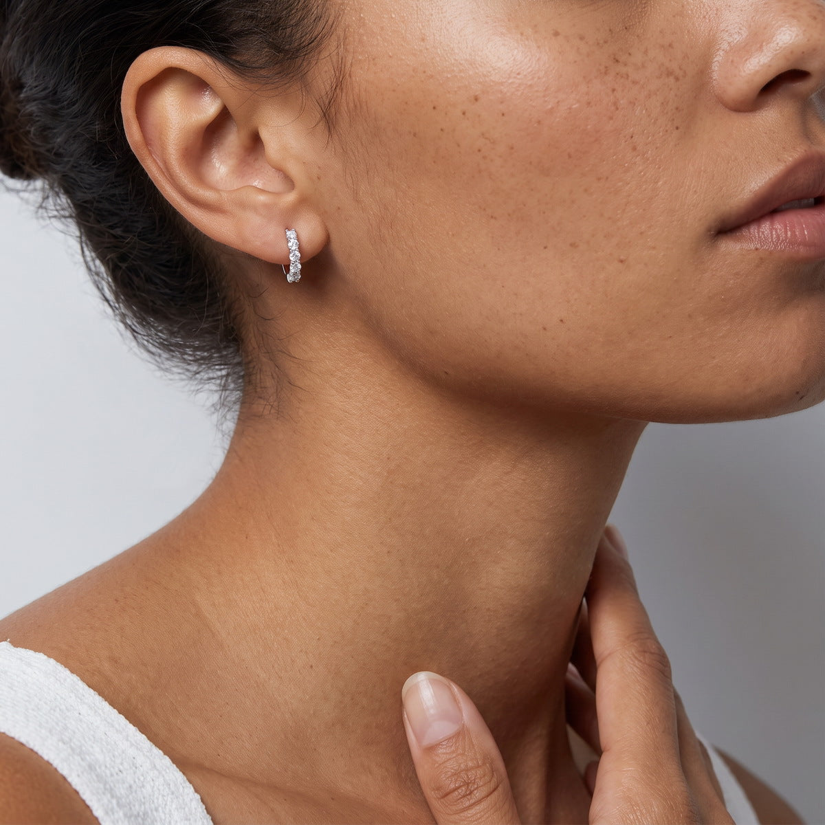 Model wearing five stone round cut lab grown diamond huggie hoop earring on earlobe