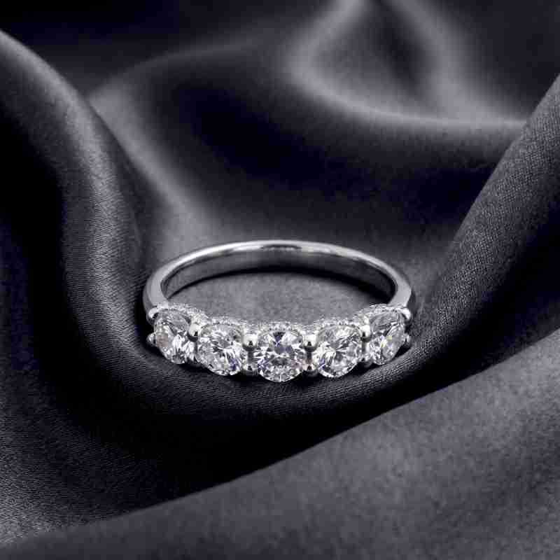 Front perspective shot of five-stone round brilliant diamond wedding band resting on dark silk.