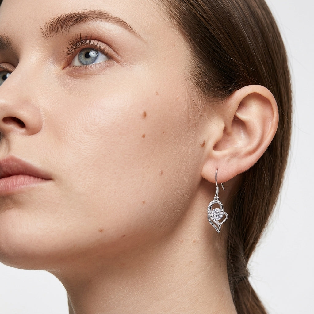 Model wearing round diamond floating open heart dangle drop earrings in side profile.