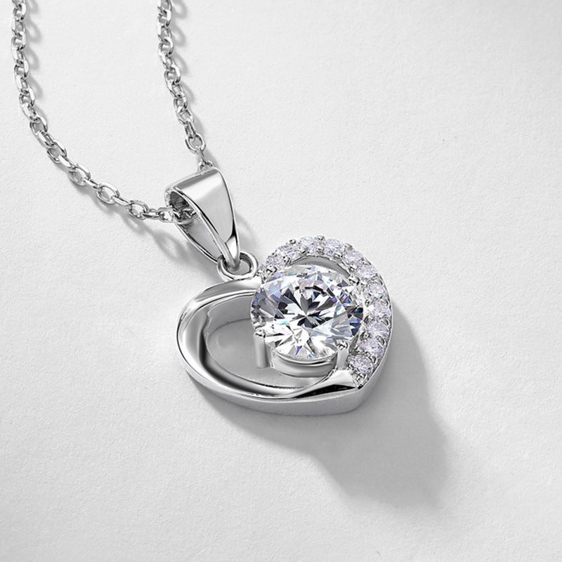 Round diamond floating heart solitaire pendant displayed on textured silver-grey background.