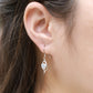 Close-up view of woman wearing round diamond floating open heart dangle earring on earlobe.