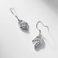 Pair of round diamond floating open heart dangle earrings on light silver backdrop.