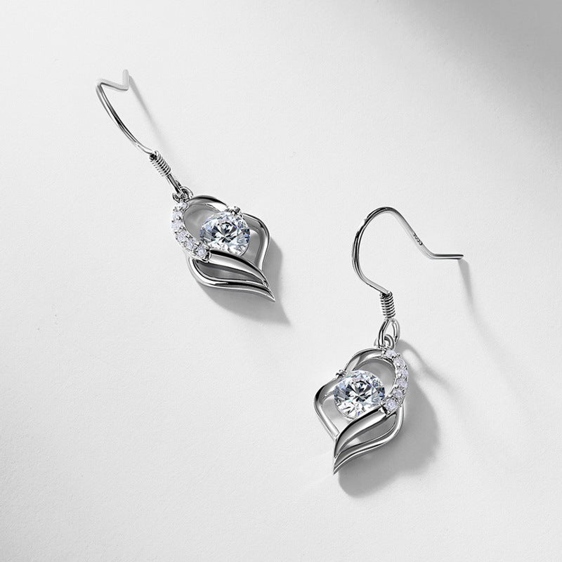 Pair of round diamond floating open heart dangle earrings on light silver backdrop.