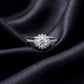 Front view of floral sunburst halo lab grown diamond engagement ring resting on dark black silk