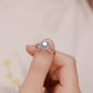 Close up of hand holding floral sunburst halo lab grown diamond ring in warm natural lighting
