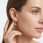 Model wearing gold ball drop moissanite huggie hoop earrings in a lifestyle photo.