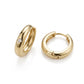 Classic gold thick huggie hoop earrings with flush set moissanite resting on a white surface.