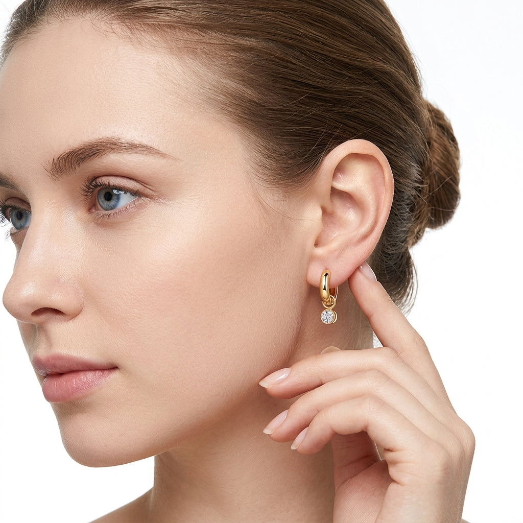 Model wearing gold tubular dangle hoop earrings with solitaire bezel moissanite in a studio portrait.