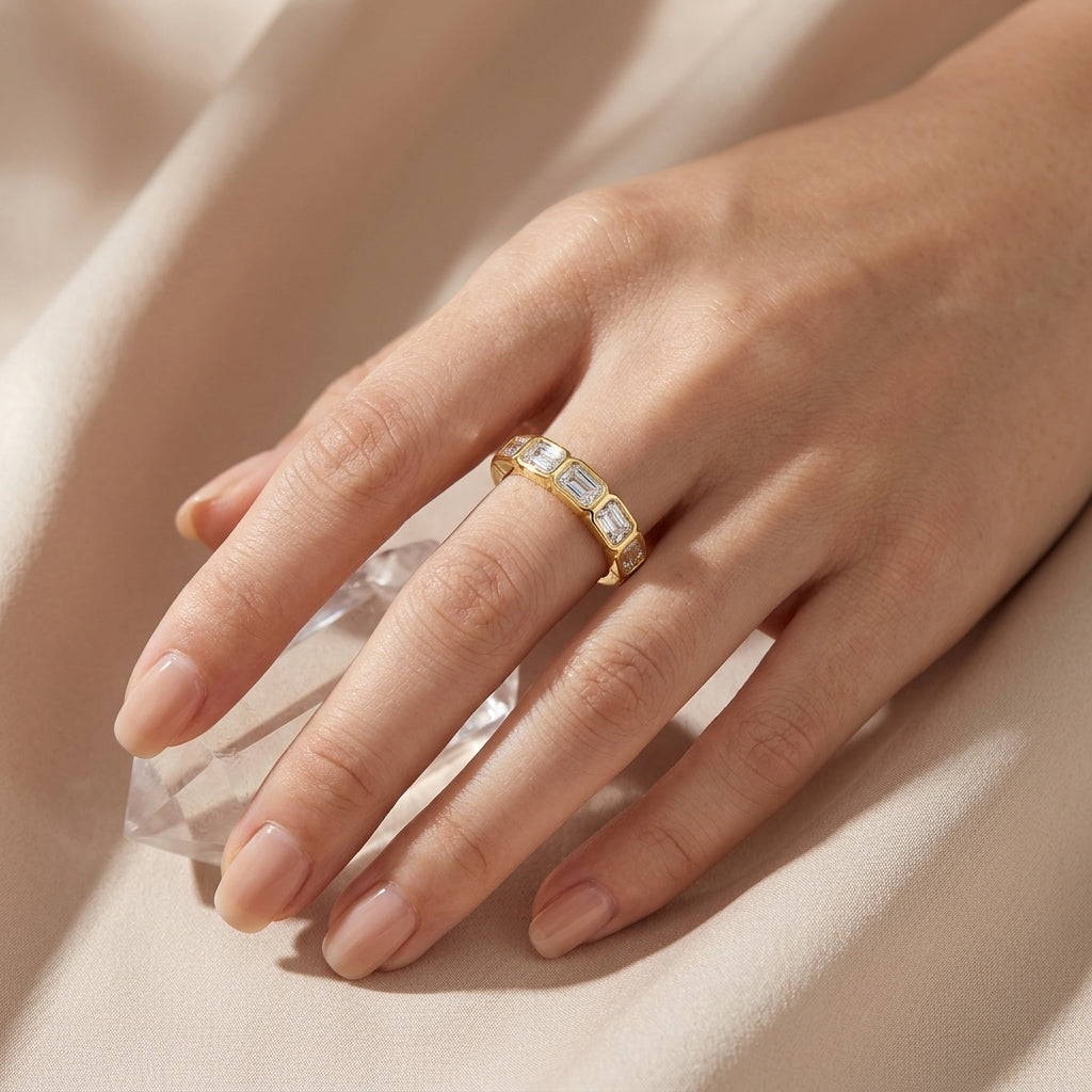 Close up shot of a hand styled with the gold emerald cut moissanite bezel eternity ring.