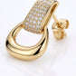 Macro close-up of gold equestrian stirrup door knocker dangle earrings with brilliant pavé moissanite.