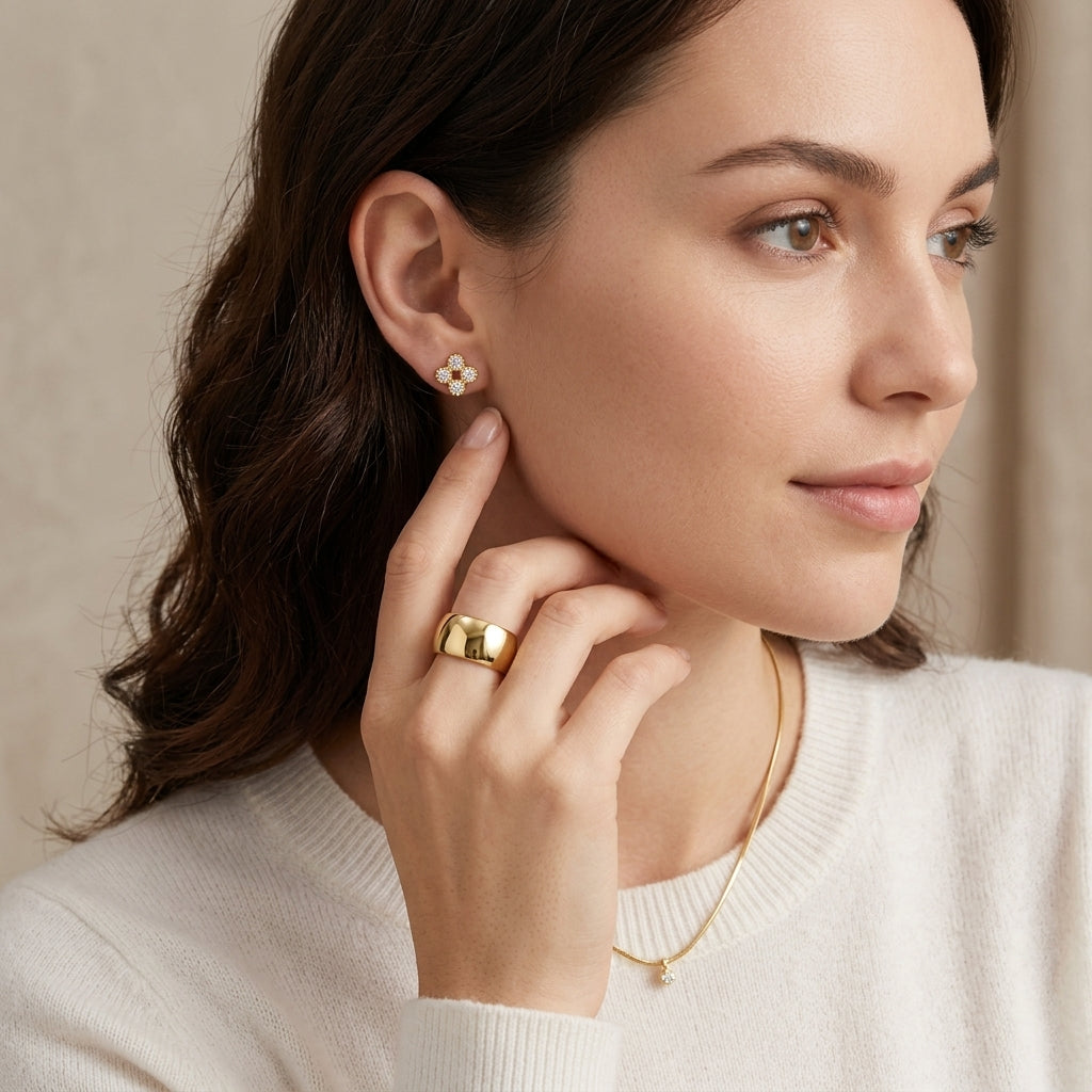 Model wearing gold round cut moissanite four-leaf clover beaded stud earrings in a daylight portrait.