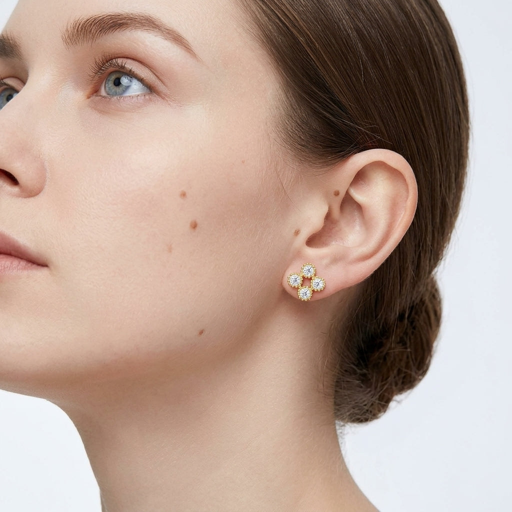 Close-up view of a model wearing gold round moissanite beaded clover stud earrings.