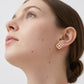 Model wearing gold round cut moissanite four-leaf clover stud earrings in a daylight studio shot.