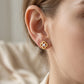 Close-up view of a model wearing gold openwork four-leaf clover moissanite stud earrings.