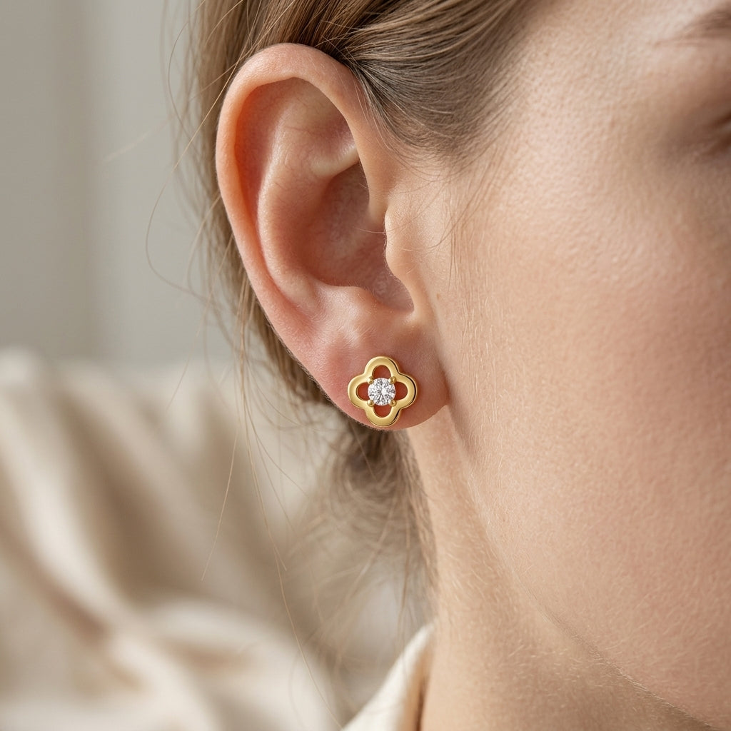 Close-up view of a model wearing gold openwork four-leaf clover moissanite stud earrings.