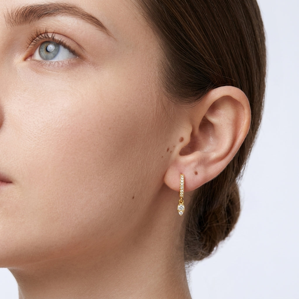 Close-up of a model wearing the gold pear pavé moissanite drop huggie earrings.