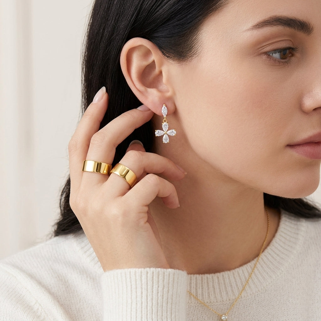 Model wearing gold pear cut moissanite floral cross dangle drop earrings in a soft lighting studio portrait.