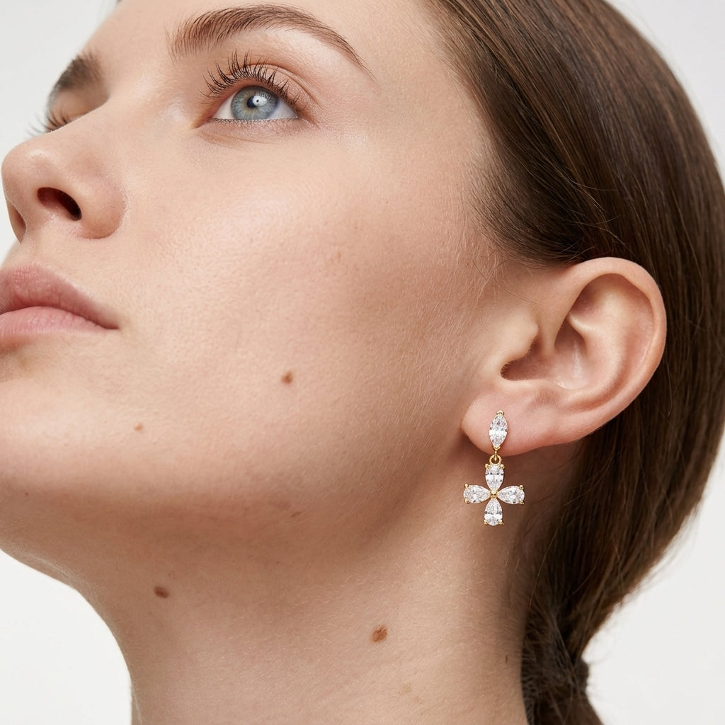 Close-up view of a model wearing gold pear cut moissanite floral cross dangle drop earrings.