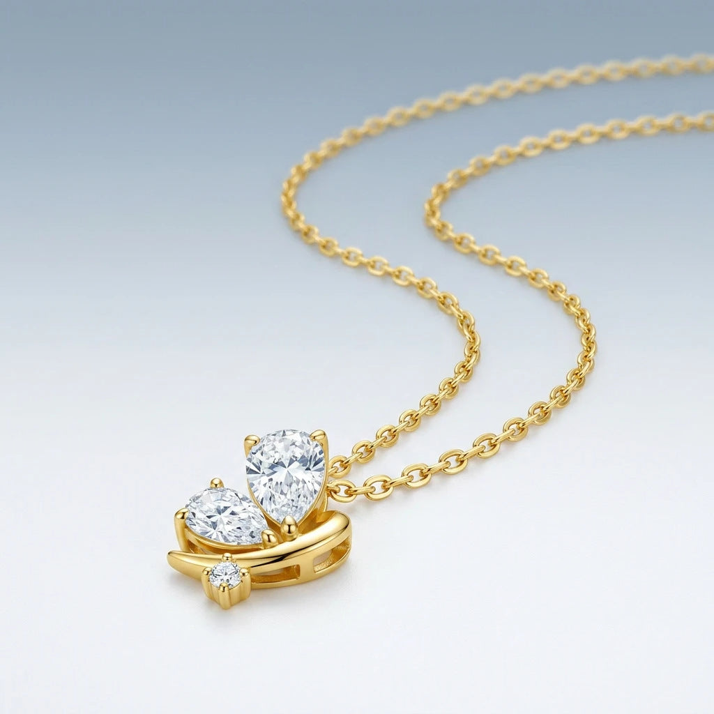 Perspective view of gold pear cut moissanite butterfly pendant necklace on slate background.