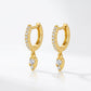 Pair of gold pavé moissanite huggie hoops with pear-shaped teardrop charms.