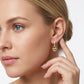 Model wearing gold puffed heart lock dangle huggie hoop earrings in a studio lifestyle portrait.