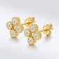 Pair of gold round cut moissanite beaded four-leaf clover stud earrings on a light blue background.