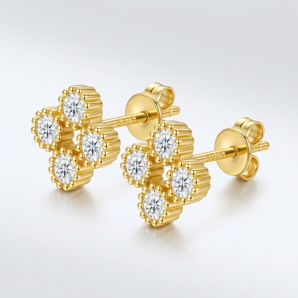 Pair of gold round cut moissanite beaded four-leaf clover stud earrings on a light blue background.