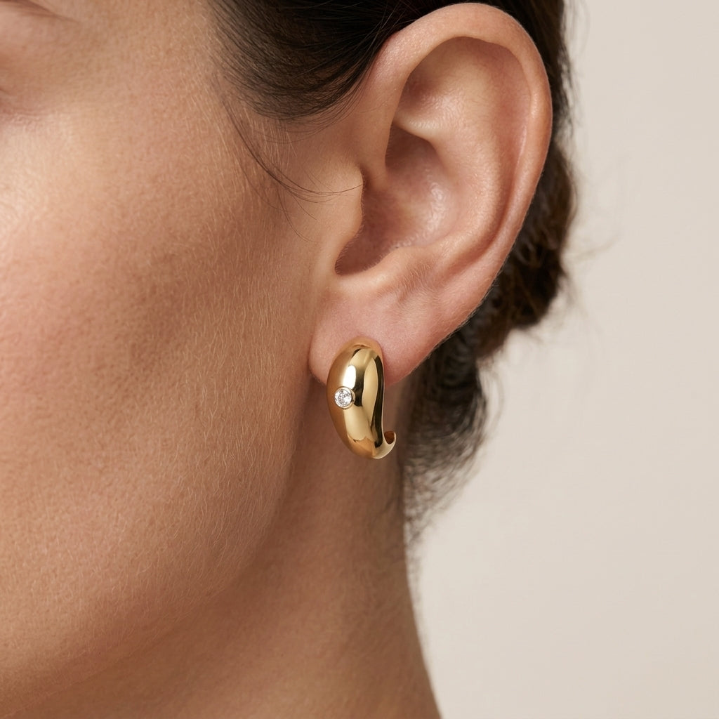 Model wearing gold sculptural teardrop moissanite earrings in a close-up ear profile.