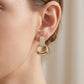 Close-up view of a model wearing gold pave moissanite stirrup door knocker dangle earrings.