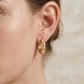 Close-up view of a model wearing classic gold thick moissanite huggie hoop earrings.