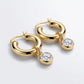 Pair of classic gold tubular dangle hoop earrings featuring round bezel-set moissanite drop charms on light gray background.